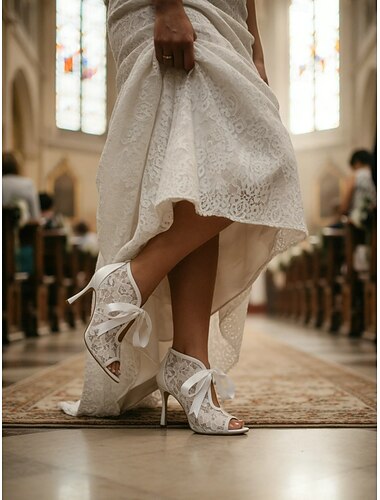  Witte kanten enkellaarsjes met open neus en satijnen strik – elegante bruidsschoenen met hoge hak.
