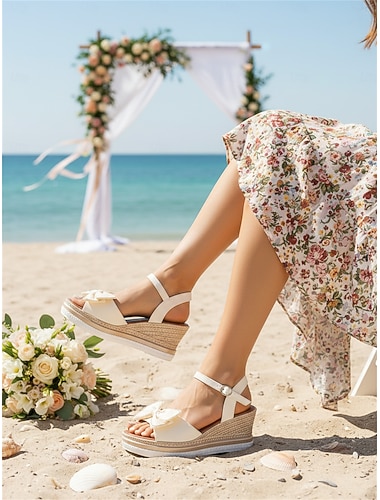  Witte damessandalen met strikdetail en sleehak – comfortabele en elegante schoenen voor strandbruiloften, perfect voor bruiden en gasten.