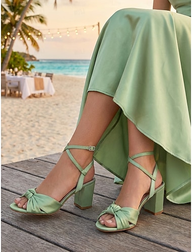  Sandales à talons carrés en satin fuchsia pour femmes, chaussures habillées à bride cheville et détail nœud, idéales pour les demoiselles d'honneur lors de mariages en plein air dans un jardin.