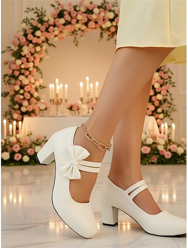  hvite damesko med mary jane-motiv og dekorativ sidesløyfe - elegante sko med rund tå og blokkhæl - sofistikerte penhæler for bryllupsgjester i byen