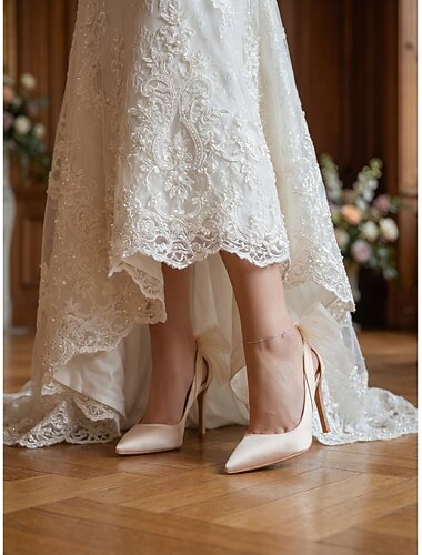  Champagnekleurige pumps met spitse neus en hoge hakken, versierd met een strik - elegante bruidspumps voor stadsbruiloften.
